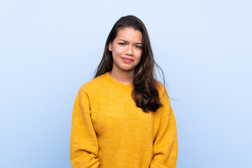 Young Colombian girl with sweater over isolated blue background with sad and depressed expression