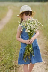 Poster portrait of cute little girl in a hat holding chamomiles bunch on the field © Albert Ziganshin