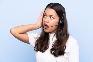 Young telemarketer Colombian woman over isolated blue background listening something