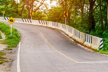 Road sign indicating steep slope and direction on cured road with nature background