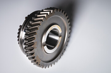 The new shiny metal gear of the switch box is fronted by a gray gradient background. The concept of new spare parts for car maintenance and repair