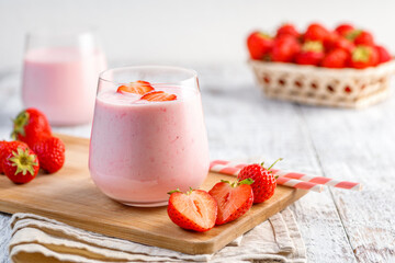 Glass with strawberry smoothie or milkshake on wooden table. Summer drink. - obrazy, fototapety, plakaty