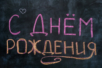 Words Happy Birthday written in Russian language on blackboard.