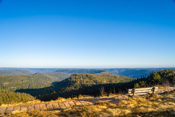 Bench at mountaintop in sunlight, looking far into the distance