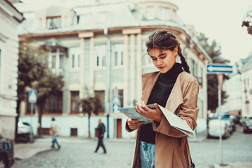 Fototapeta premium Charming female in foreign city with map in hands, full of energy and inspiration to see as much as possible cool places.