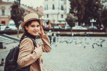 Fototapeta premium Lovely young girl in straw hat and with backpack behind shoulders, looking at the camera with big desire to see the world.