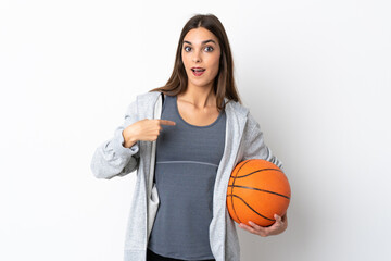 Young woman playing basketball isolated on white background with surprise facial expression