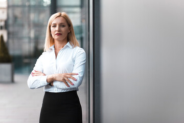 Beautiful pensive lady office employee stands arms crossed