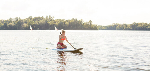 Young attractive woman on stand up paddle board in the lake, SUP