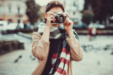 Defocused shot of creative caucasian girl watching cityscape and taking pictures of local architecture.