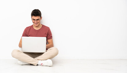 Teenager man sitting on the flor with his laptop