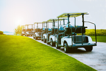 Golf cart on golf course, parking on fairway. Equipment and golf club bag are put in ready for golfer to player in field with sunlight rays background © APstudio