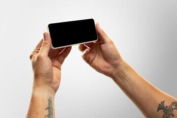 New rules for safety. Close up male hands holding phone with blank screen during online watching of popular sport matches, championships. Copyspace for ad. Devices, gadgets, technologies concept.