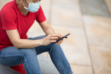 Asian woman sit on skateboard using smartphone in modern city