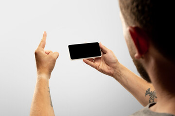 Sincere fun. Close up male hands holding phone with blank screen during online watching of popular sport matches, championships. Copyspace for ad. Devices, gadgets, technologies concept.