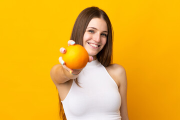 Young caucasian woman holding an orange isolated on orange background