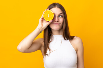 Young caucasian woman holding an orange isolated on orange background