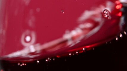 Close up swirling red wine in wineglass over red - Powered by Adobe