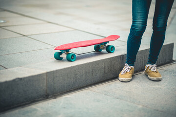 Fototapeta na wymiar Asian woman with skatebaord in modern city