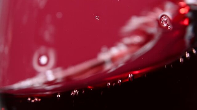Close up swirling red wine in wineglass over red