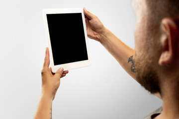 Naklejka premium Close up male hands holding tablet with blank screen during online watching of popular sport matches, championships. Copyspace for advertising. Devices, gadgets, technologies concept.