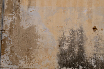 Old grunge cracked concrete wall with some stains and holes. White brown and orange collors.