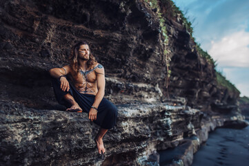 European man with drawings on his body walks among the rocks