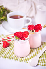 Two portions natural homemade yogurt in a glass jar with fresh raspberry. Breakfast concept
