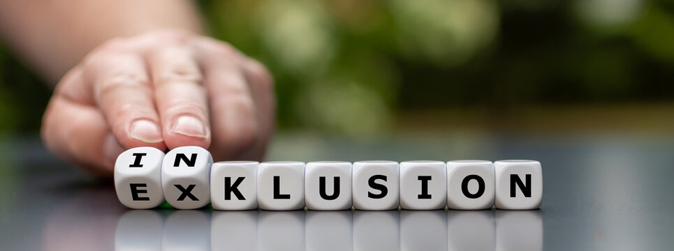 Symbol for a better inclusion. Hand turns dice and changes the German word "Exklusion" (exclusion) to "Inklusion" (inclusion).