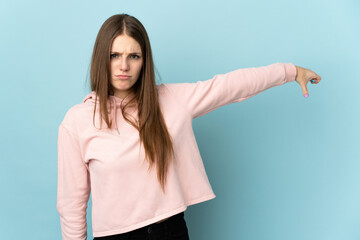 Young caucasian woman isolated on blue background showing thumb down with negative expression