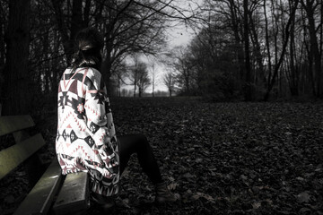 The back of an anonymous brown-haired girl, who's staring in the distance, in a dark and scary...