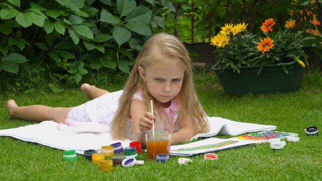 Little girl paints a picture. The process of creativity in a child. Girl paints paints