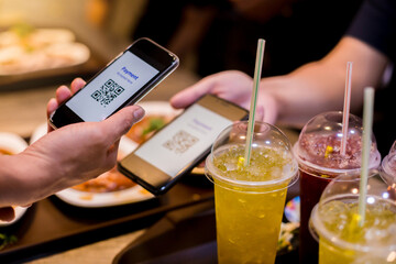 Selective focus to smart phone in hand to scan QR code tag with blurry food, dessert and customers...