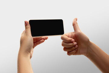 Thumb up, like. Close up female hands holding smartphone with blank screen during online watching of popular sport matches, championships. Copyspace for ad. Devices, gadgets, technologies concept.
