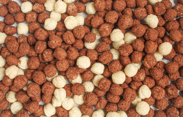 Full screen of delicious round cornflakes. Brown and white chocolate cereals mixed
