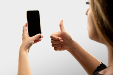 Thumb up, like. Close up female hands holding smartphone with blank screen during online watching of popular sport matches, championships. Copyspace for ad. Devices, gadgets, technologies concept.