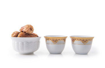 Traditional Arabic black coffee cups with bowl of sweet dates. Isolated front view of Arabic coffee cups.