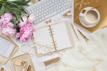 Women's diary and golden stationery. Bouquet of pink peonies. Glasses, a white keyboard, pen,...