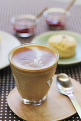 cup of coffee with scone and jam in background