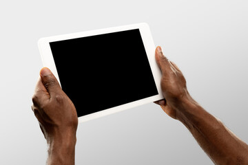 Watching, scrolling. Close up male hands holding tablet with blank screen during online watching of popular sport matches, championships. Copyspace for ad. Devices, gadgets, technologies concept.