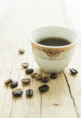 A traditional cup of Arabic coffee and coffee beans scattered. Middle Eastern food and drink.