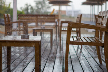 It's raining on the beach bar. The wooden salt shaker and wooden table are completely wet as is the ashtray on the table. The rain fell suddenly and the guests left.