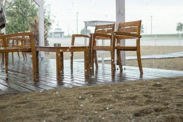 Focus on wet wooden tables and chairs in a beach cafe. The weather was easily bad and it rained suddenly.