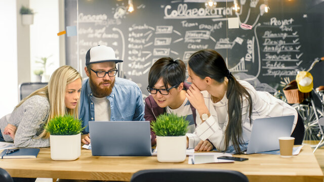 Diverse Team of Young Women and Men Developers Have Team Meeting Using Laptop. Beautiful Young People in Bright Modern Office Environment.