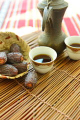 Arabic dates in a bowl with black coffee - close up. Kahva, a traditional Middle Eastern beverage with date fruits.  