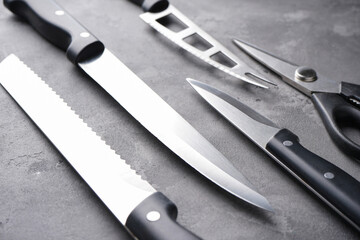 Various kitchen utensils on a gray table background, close-up. A set of knives.