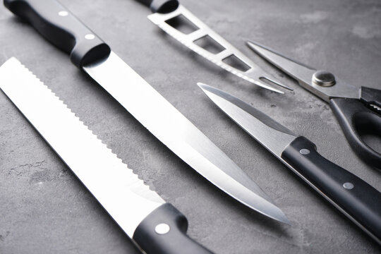 Various kitchen utensils on a gray table background, close-up. A set of knives.