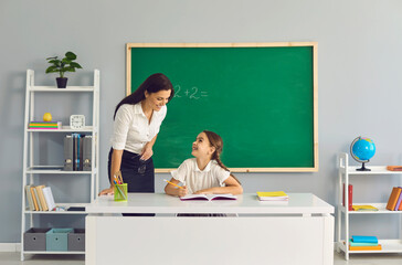 Teacher teaches a schoolgirl in the classroom. Back to school.