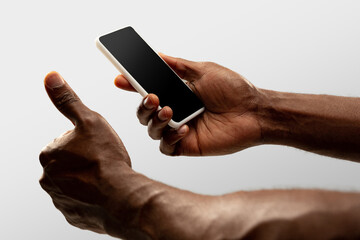 Thumb up, like. Close up male hands holding smartphone with blank screen during online watching of popular sport matches, championships. Copyspace for ad. Devices, gadgets, technologies concept.