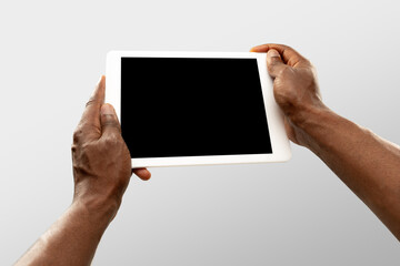 Watching, scrolling. Close up male hands holding tablet with blank screen during online watching of popular sport matches, championships. Copyspace for ad. Devices, gadgets, technologies concept.